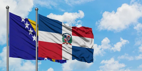 Bandera de Bosnia Herzegovina y República Dominicana ondeando en el viento contra el cielo azul nublado blanco juntos. Concepto diplomático, relaciones internacionales . — Foto de Stock