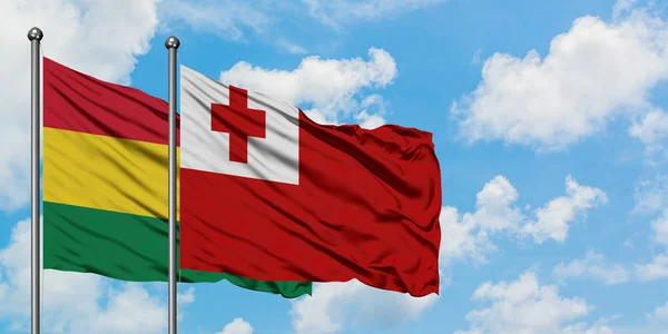 Bandera de Bolivia y Tonga ondeando en el viento contra el cielo azul nublado blanco juntos. Concepto diplomático, relaciones internacionales . — Foto de Stock