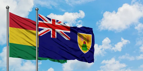 Bandera de Bolivia y las Islas Turcas y Caicos ondeando en el viento contra el cielo azul nublado blanco juntos. Concepto diplomático, relaciones internacionales . — Foto de Stock