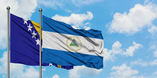 Bosnien-Herzegowina und Nicaragua schwenken gemeinsam die Flagge im Wind vor dem wolkenverhangenen blauen Himmel. Diplomatie-Konzept, internationale Beziehungen. — Stockfoto