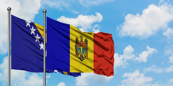 Bandera de Bosnia Herzegovina y Moldavia ondeando en el viento contra el cielo azul nublado blanco juntos. Concepto diplomático, relaciones internacionales . — Foto de Stock