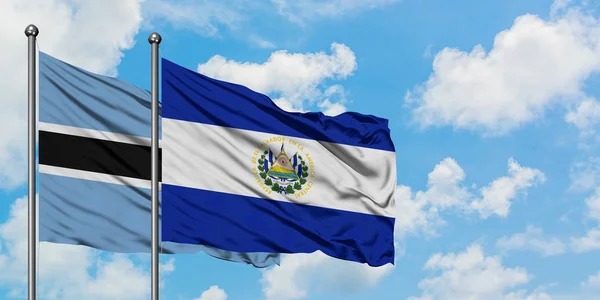 Bandera de Botswana y El Salvador ondeando en el viento contra el cielo azul nublado blanco juntos. Concepto diplomático, relaciones internacionales . —  Fotos de Stock