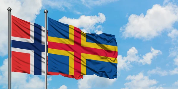Bouvet Adaları ve Aland Adaları bayrağı birlikte beyaz bulutlu mavi gökyüzüne karşı rüzgarda sallayarak. Diplomasi kavramı, uluslararası ilişkiler. — Stok fotoğraf