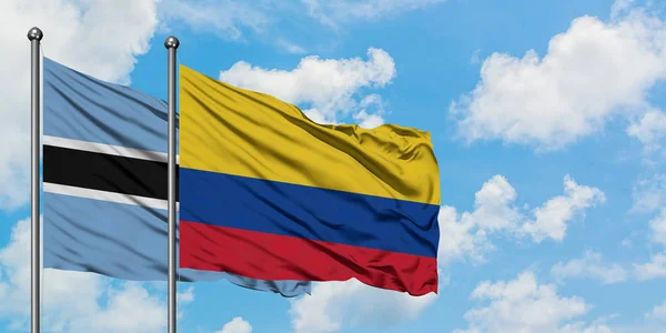 Bandera de Botswana y Colombia ondeando en el viento contra el cielo azul nublado blanco juntos. Concepto diplomático, relaciones internacionales . — Foto de Stock