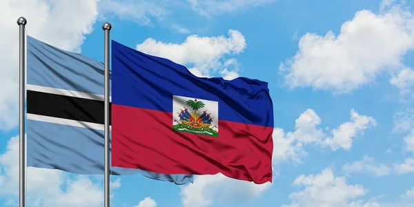 Botswana en Haïti vlag zwaaien in de wind tegen witte bewolkte blauwe hemel samen. Diplomatie concept, internationale betrekkingen. — Stockfoto