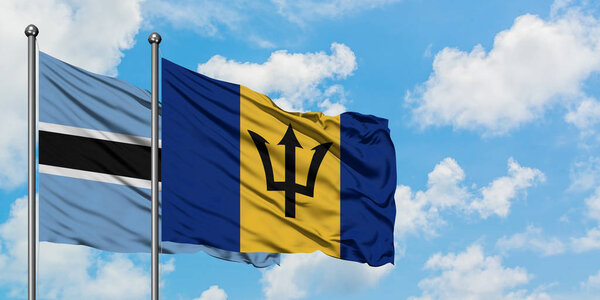 Botswana and Barbados flag waving in the wind against white cloudy blue sky together. Diplomacy concept, international relations.