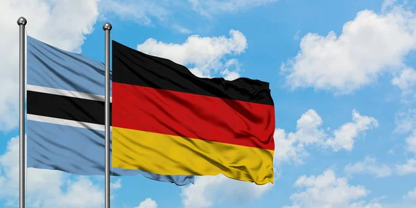 Bandera de Botswana y Alemania ondeando en el viento contra el cielo azul nublado blanco juntos. Concepto diplomático, relaciones internacionales . — Foto de Stock