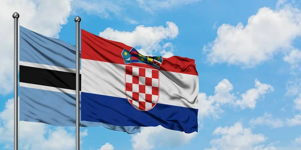 Botswana a chorvatská vlajka mávali ve větru proti bíle zatažené modré obloze. Diplomacie, mezinárodní vztahy. — Stock fotografie
