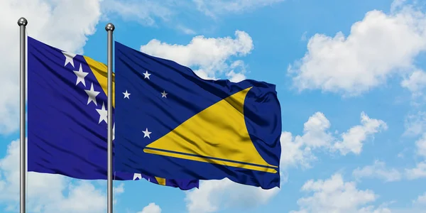 Η Βοσνία Ερζεγοβίνη και η σημαία του Τοκέλου χαιρετούν στον άνεμο ενάντια στον λευκό συννεφιασμένο γαλάζιο ουρανό. Φιλοσοφία της διπλωματίας, διεθνείς σχέσεις. — Φωτογραφία Αρχείου