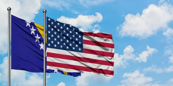 Bósnia-Herzegovina e Estados Unidos acenando com a bandeira no vento contra o céu azul nublado branco juntos. Conceito de diplomacia, relações internacionais . — Fotografia de Stock