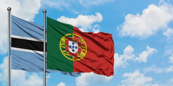 Bandera de Botswana y Portugal ondeando en el viento contra el cielo azul nublado blanco juntos. Concepto diplomático, relaciones internacionales . — Foto de Stock