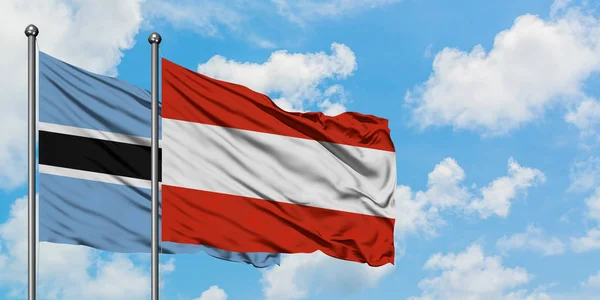 一緒に白い曇った青い空に対して風に手を振るボツワナとオーストリアの旗。外交概念、国際関係. — ストック写真