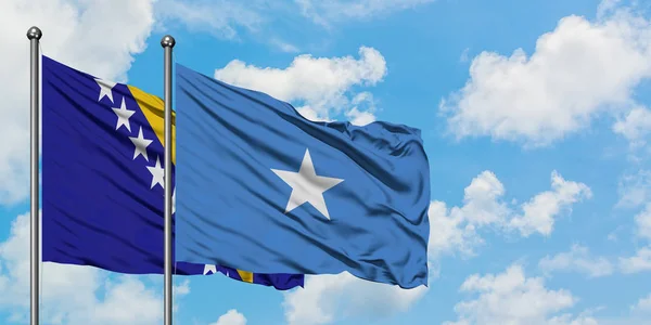 Bandera de Bosnia Herzegovina y Somalia ondeando en el viento contra el cielo azul nublado blanco juntos. Concepto diplomático, relaciones internacionales . — Foto de Stock