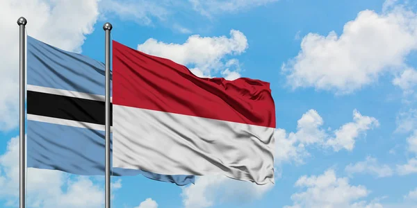 Botswana e Indonesia sventolano bandiera nel vento contro bianco cielo blu nuvoloso insieme. Concetto di diplomazia, relazioni internazionali . — Foto Stock