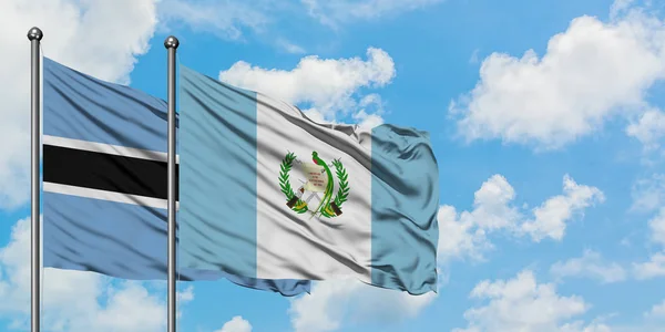 Bandera de Botswana y Guatemala ondeando en el viento contra el cielo azul nublado blanco juntos. Concepto diplomático, relaciones internacionales . — Foto de Stock
