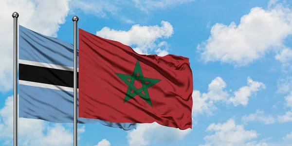 Bandera de Botswana y Marruecos ondeando en el viento contra el cielo azul nublado blanco juntos. Concepto diplomático, relaciones internacionales . — Foto de Stock