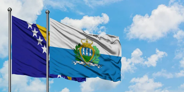 Bandera de Bosnia Herzegovina y San Marino ondeando en el viento contra el cielo azul nublado blanco juntos. Concepto diplomático, relaciones internacionales . — Foto de Stock