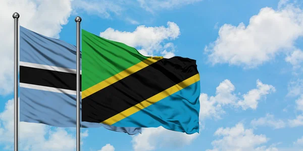 Botsvana ve Tanzanya bayrağı birlikte beyaz bulutlu mavi gökyüzüne karşı rüzgarda sallayarak. Diplomasi kavramı, uluslararası ilişkiler. — Stok fotoğraf