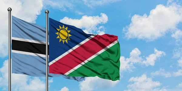 Bandera de Botswana y Namibia ondeando en el viento contra el cielo azul nublado blanco juntos. Concepto diplomático, relaciones internacionales . — Foto de Stock