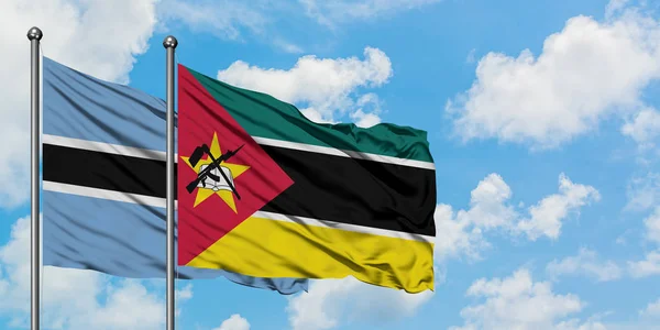 一緒に白い曇った青い空に対して風に手を振るボツワナとモザンビークの旗。外交概念、国際関係. — ストック写真