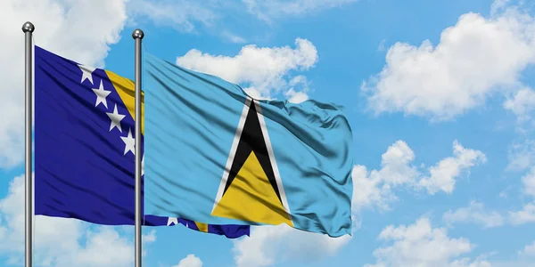 Bandera de Bosnia Herzegovina y Santa Lucía ondeando en el viento contra el cielo azul nublado blanco juntos. Concepto diplomático, relaciones internacionales . — Foto de Stock