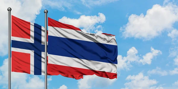 Bouvet Islands e bandiera thailandese sventolano insieme nel vento contro il bianco cielo blu nuvoloso. Concetto di diplomazia, relazioni internazionali . — Foto Stock