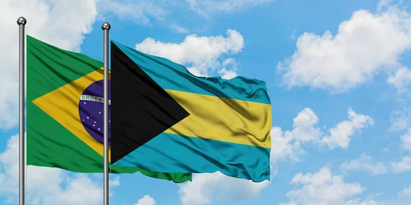 Bandera de Brasil y Bahamas ondeando en el viento contra el cielo azul nublado blanco juntos. Concepto diplomático, relaciones internacionales . — Foto de Stock