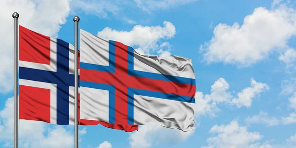 Bandera de las Islas Bouvet y las Islas Feroe ondeando en el viento contra el cielo azul nublado blanco juntos. Concepto diplomático, relaciones internacionales . — Foto de Stock