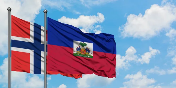 ブーヴェ諸島とハイチの旗は、一緒に白い曇り青い空に対して風に手を振る。外交概念、国際関係. — ストック写真