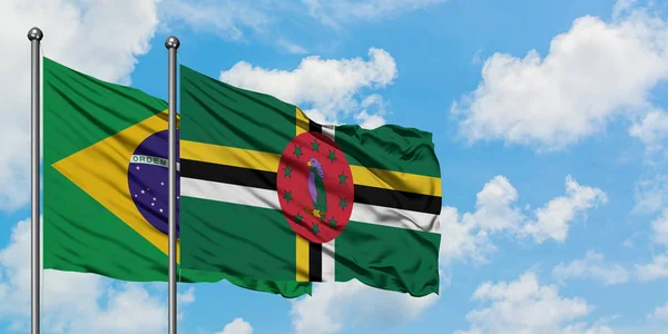 Bandera de Brasil y Dominica ondeando en el viento contra el cielo azul nublado blanco juntos. Concepto diplomático, relaciones internacionales . —  Fotos de Stock