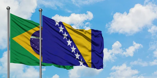 Bandera de Brasil y Bosnia Herzegovina ondeando en el viento contra el cielo azul nublado blanco juntos. Concepto diplomático, relaciones internacionales . — Foto de Stock