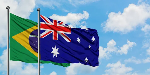 Bandera de Brasil y Australia ondeando en el viento contra el cielo azul nublado blanco juntos. Concepto diplomático, relaciones internacionales . — Foto de Stock