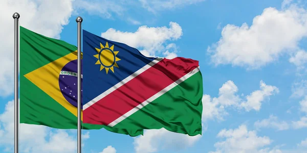 Drapeau du Brésil et de la Namibie agitant dans le vent contre ciel bleu nuageux blanc ensemble. Concept de diplomatie, relations internationales . — Photo