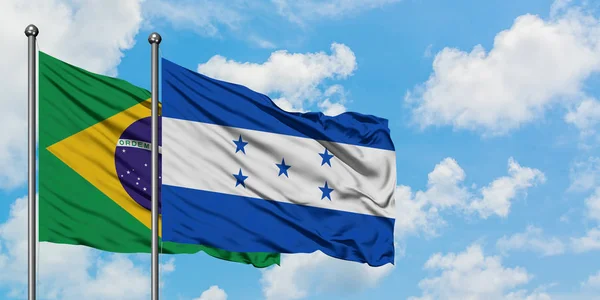 Brazílie a Honduraská vlajka mávali ve větru proti bíle zatažené modré obloze. Diplomacie, mezinárodní vztahy. — Stock fotografie