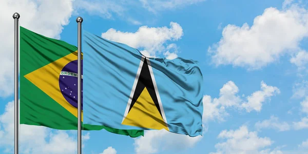 Bandera de Brasil y Santa Lucía ondeando en el viento contra el cielo azul nublado blanco juntos. Concepto diplomático, relaciones internacionales . —  Fotos de Stock