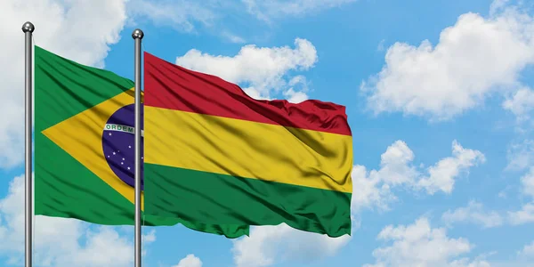 Bandera de Brasil y Bolivia ondeando en el viento contra el cielo azul nublado blanco juntos. Concepto diplomático, relaciones internacionales . — Foto de Stock