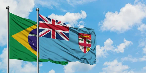 Bandera de Brasil y Fiyi ondeando en el viento contra el cielo azul nublado blanco juntos. Concepto diplomático, relaciones internacionales . — Foto de Stock