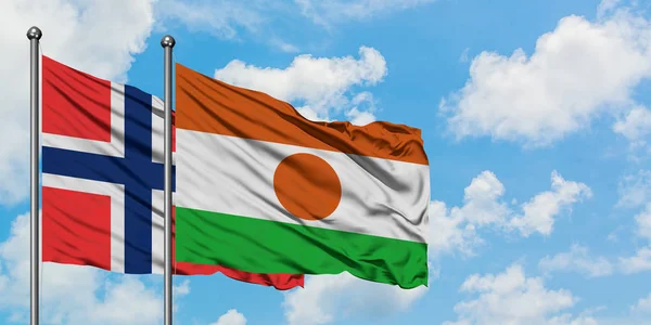 Bandera de las islas Bouvet y Níger ondeando en el viento contra el cielo azul nublado blanco juntos. Concepto diplomático, relaciones internacionales . — Foto de Stock