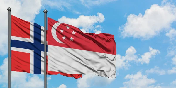 Bandera de las Islas Bouvet y Singapur ondeando en el viento contra el cielo azul nublado blanco juntos. Concepto diplomático, relaciones internacionales . — Foto de Stock