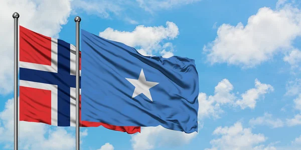 Bandera de las islas Bouvet y Somalia ondeando en el viento contra el cielo azul nublado blanco juntos. Concepto diplomático, relaciones internacionales . — Foto de Stock