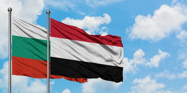 Bandera de Bulgaria y Yemen ondeando en el viento contra el cielo azul nublado blanco juntos. Concepto diplomático, relaciones internacionales . — Foto de Stock