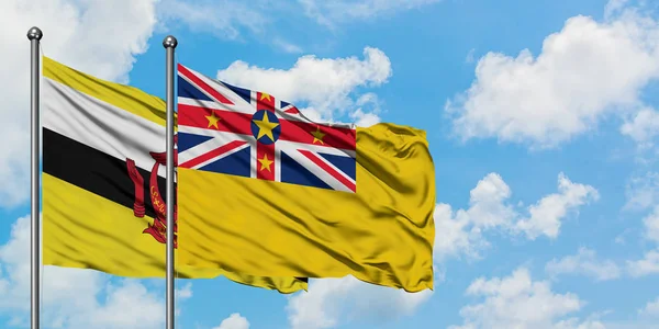 文莱和纽埃国旗在风中飘扬，白云蓝天相聚。外交概念、国际关系. — 图库照片