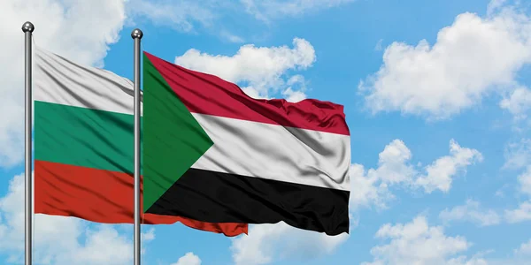 Bandera de Bulgaria y Sudán ondeando en el viento contra el cielo azul nublado blanco juntos. Concepto diplomático, relaciones internacionales . — Foto de Stock