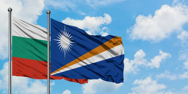Bandera de Bulgaria y las Islas Marshall ondeando en el viento contra el cielo azul nublado blanco juntos. Concepto diplomático, relaciones internacionales . — Foto de Stock