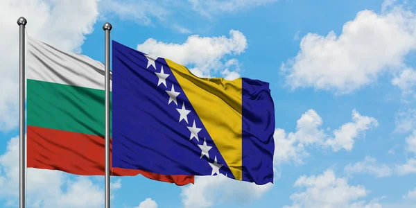 Bandera de Bulgaria y Bosnia Herzegovina ondeando en el viento contra el cielo azul nublado blanco juntos. Concepto diplomático, relaciones internacionales . — Foto de Stock