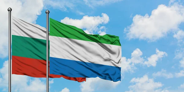 Bandera de Bulgaria y Sierra Leona ondeando en el viento contra el cielo azul nublado blanco juntos. Concepto diplomático, relaciones internacionales . — Foto de Stock