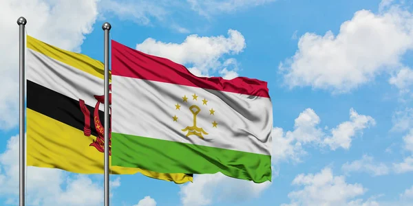 Bandera de Brunei y Tayikistán ondeando en el viento contra el cielo azul nublado blanco juntos. Concepto diplomático, relaciones internacionales . — Foto de Stock