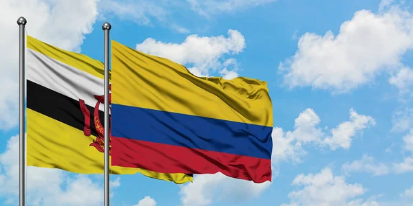 Bandera de Brunei y Colombia ondeando en el viento contra el cielo azul nublado blanco juntos. Concepto diplomático, relaciones internacionales . — Foto de Stock