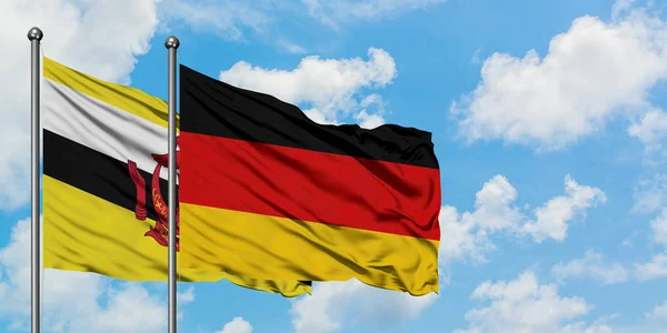 Bandera de Brunéi y Alemania ondeando en el viento contra el cielo azul nublado blanco juntos. Concepto diplomático, relaciones internacionales . — Foto de Stock