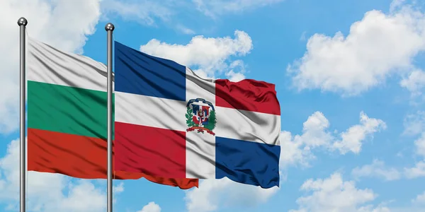 Bulgária e República Dominicana bandeira acenando no vento contra o céu azul nublado branco juntos. Conceito de diplomacia, relações internacionais . — Fotografia de Stock